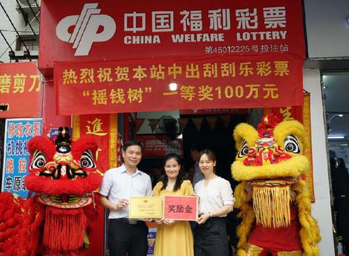 图为：南宁市福彩中心工作人员为投注站业主颁发中奖牌匾和奖励金