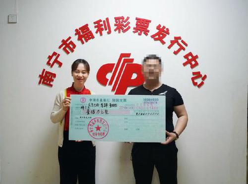 图为：南宁市福彩中心工作人员为梅先生颁奖